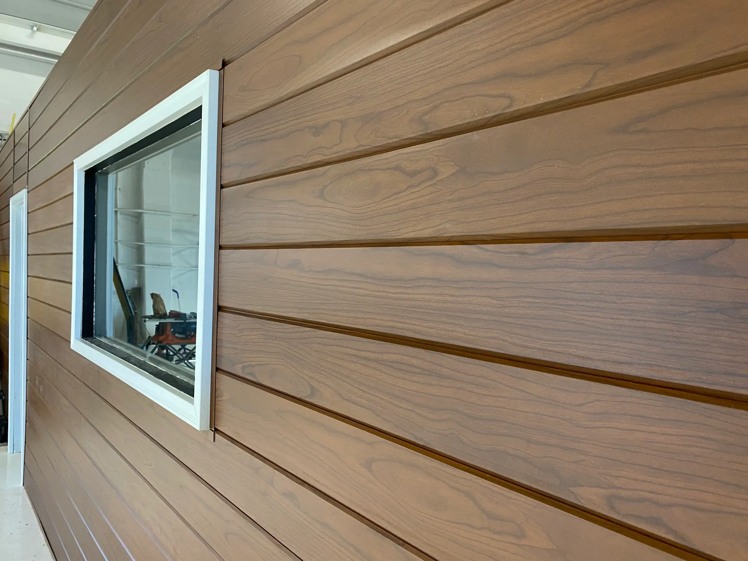 Exterior wall clad in AFX woodgrain aluminum panels around a white-framed window