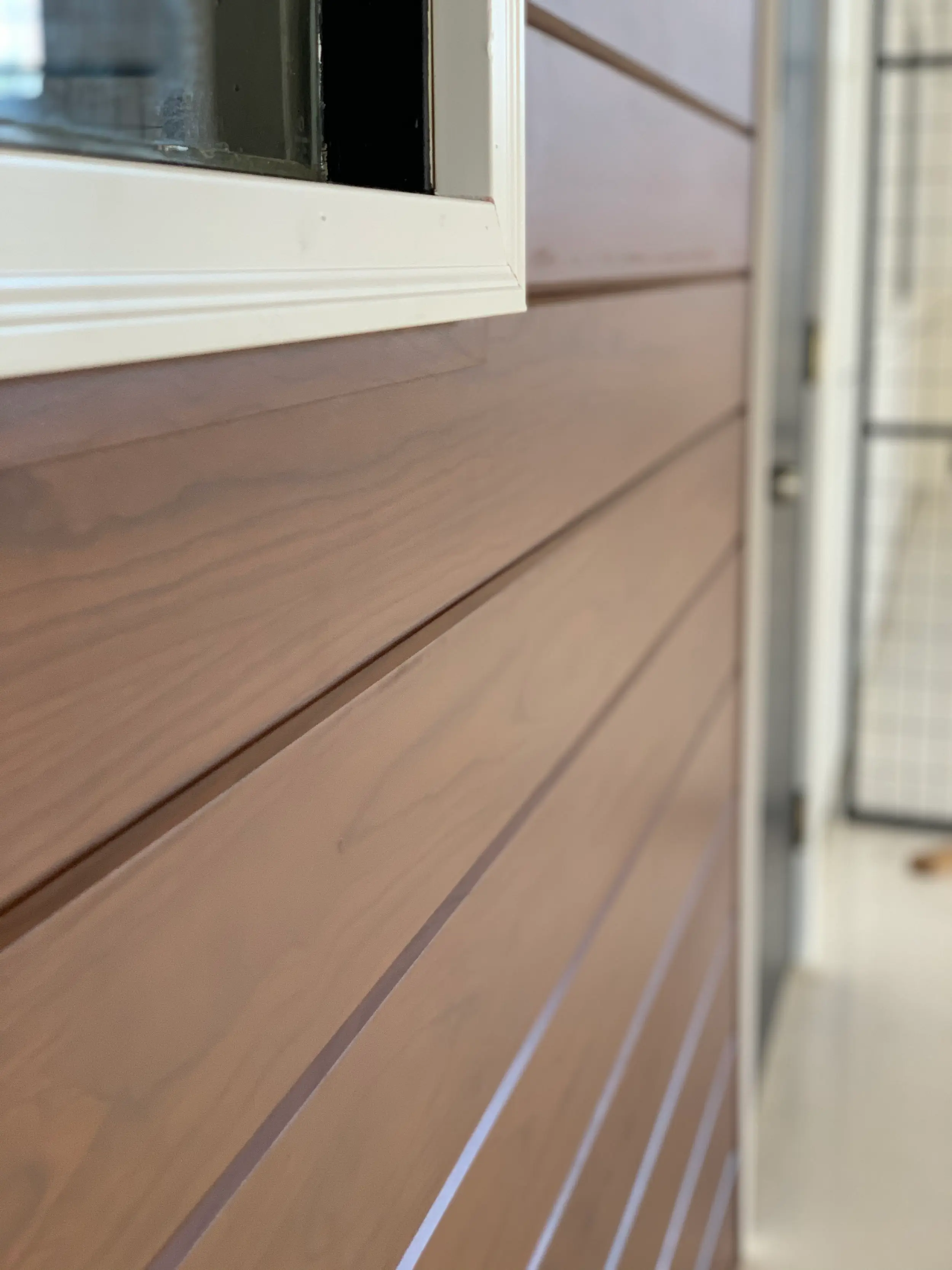 Building entry with AFX woodgrain aluminum cladding beside a glass door
