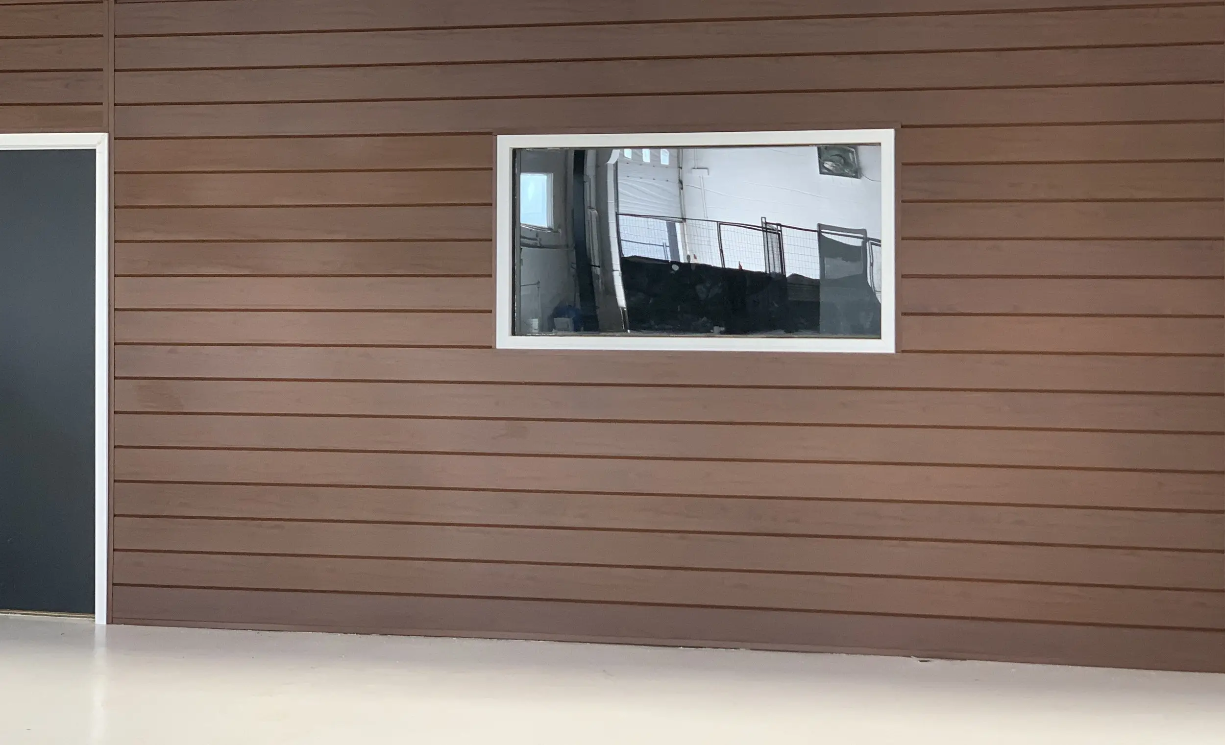 Feature wall clad in dark AFX woodgrain aluminum around a window opening