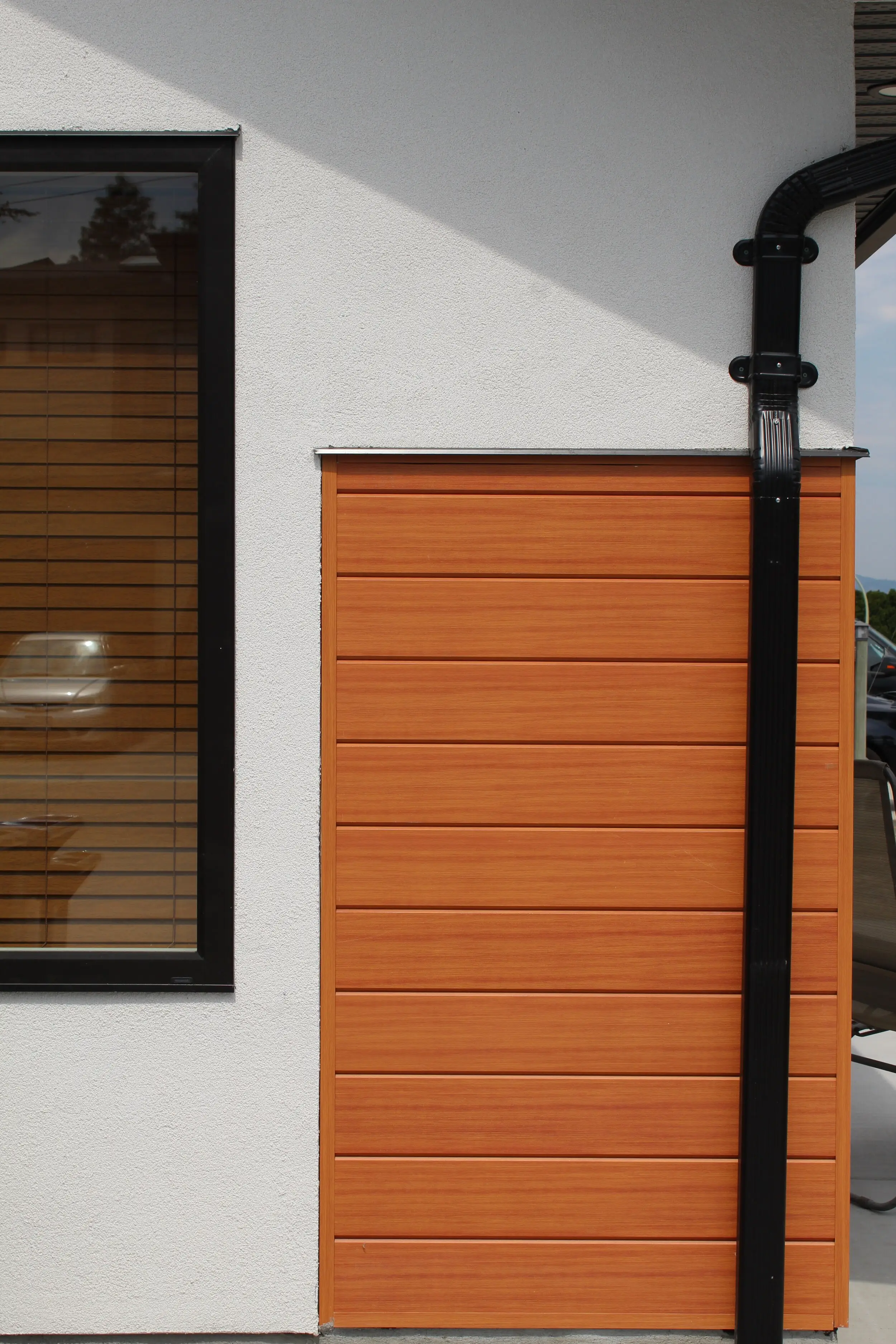 Section of AFX woodgrain aluminum cladding beside a black downspout