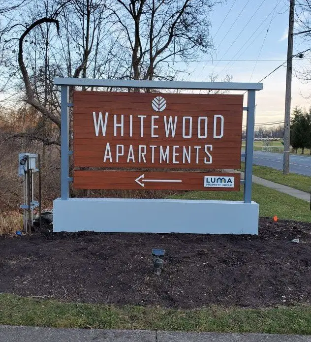 Whitewood Apartments entry sign with an AFX woodgrain aluminum panel